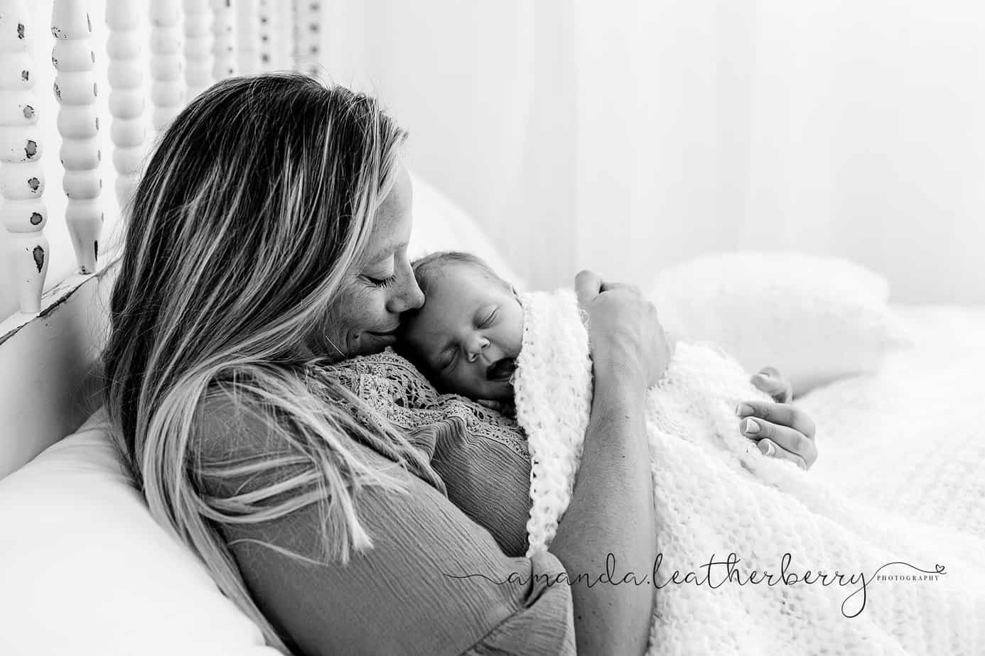 mom and newborn cuddling in bed during pensacola studio portrait session