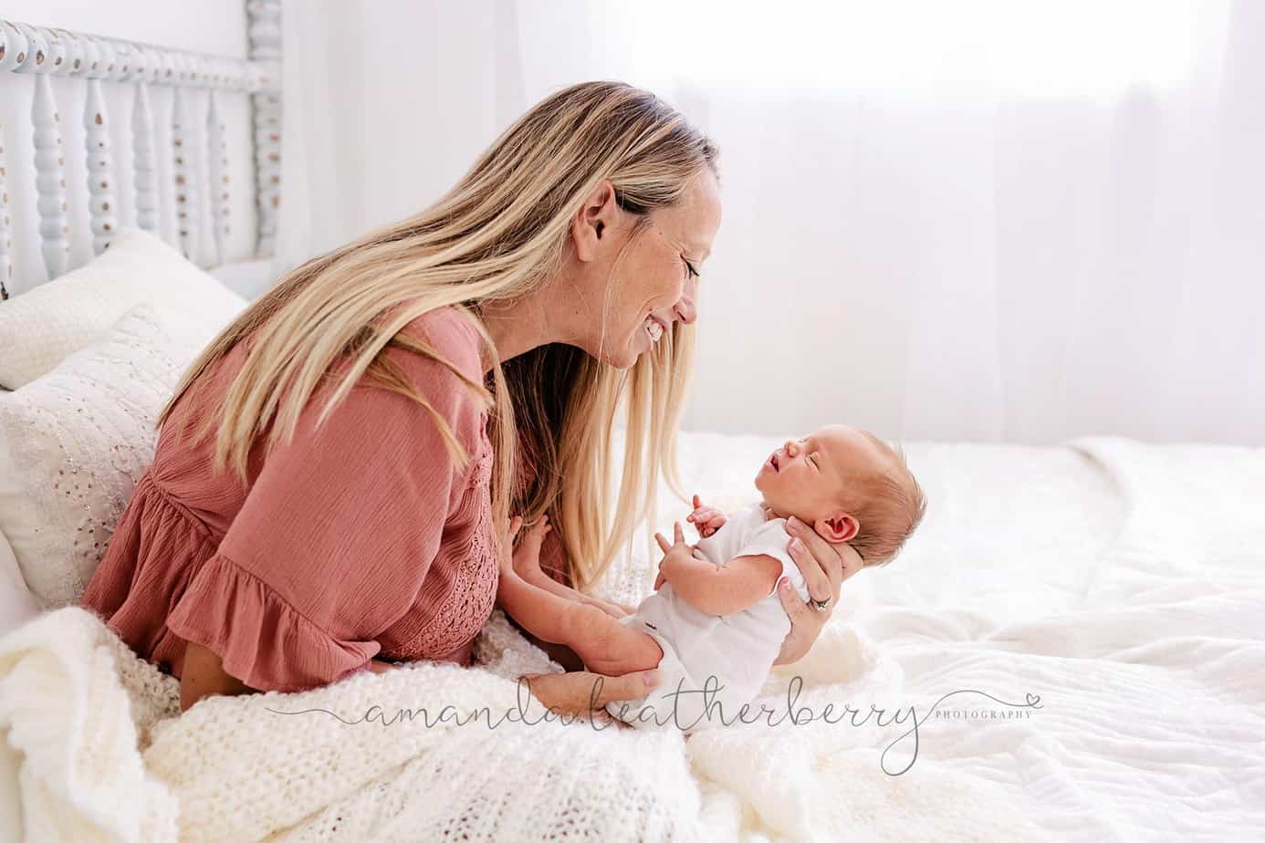 mom and newborn cuddling in bed during pensacola studio portrait session