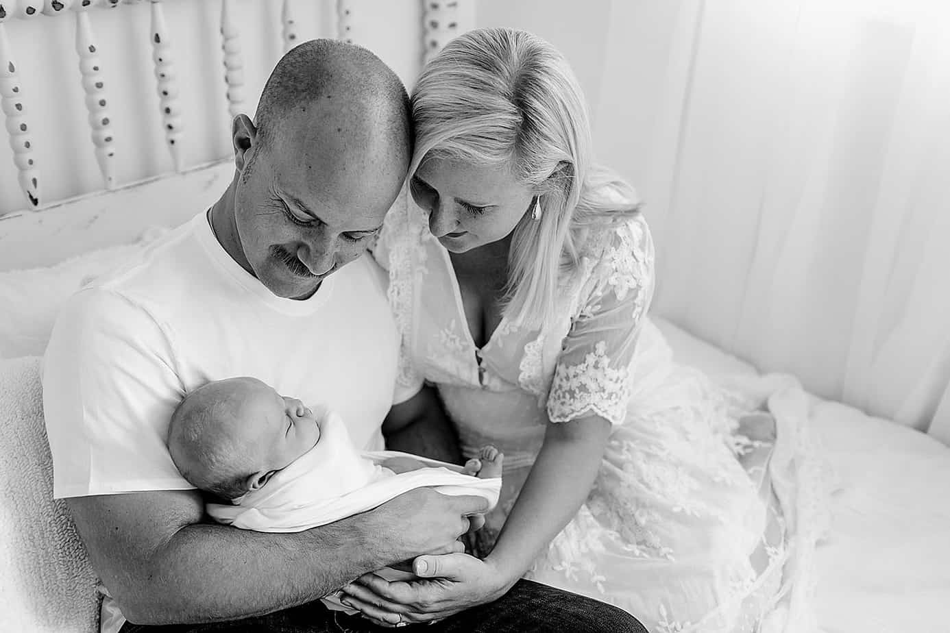 mom and dad with newborn on bed pensacola photography