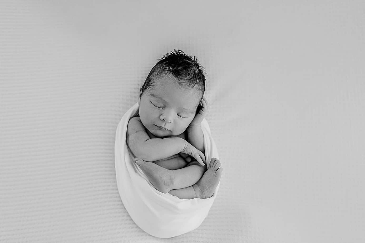 Newborn baby girl wrapped in white in pensacola photography studio