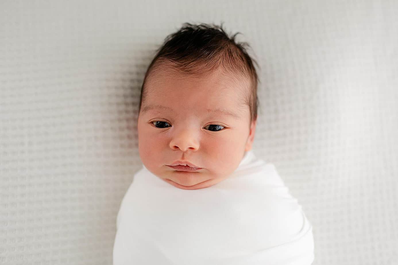 awake newborn baby on white in pensacola photography studio